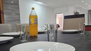 A dining table with plates, glasses, and a bottle of soda.
