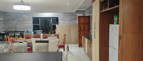 A modern kitchen with a dining area, wooden cabinets, and a refrigerator.
