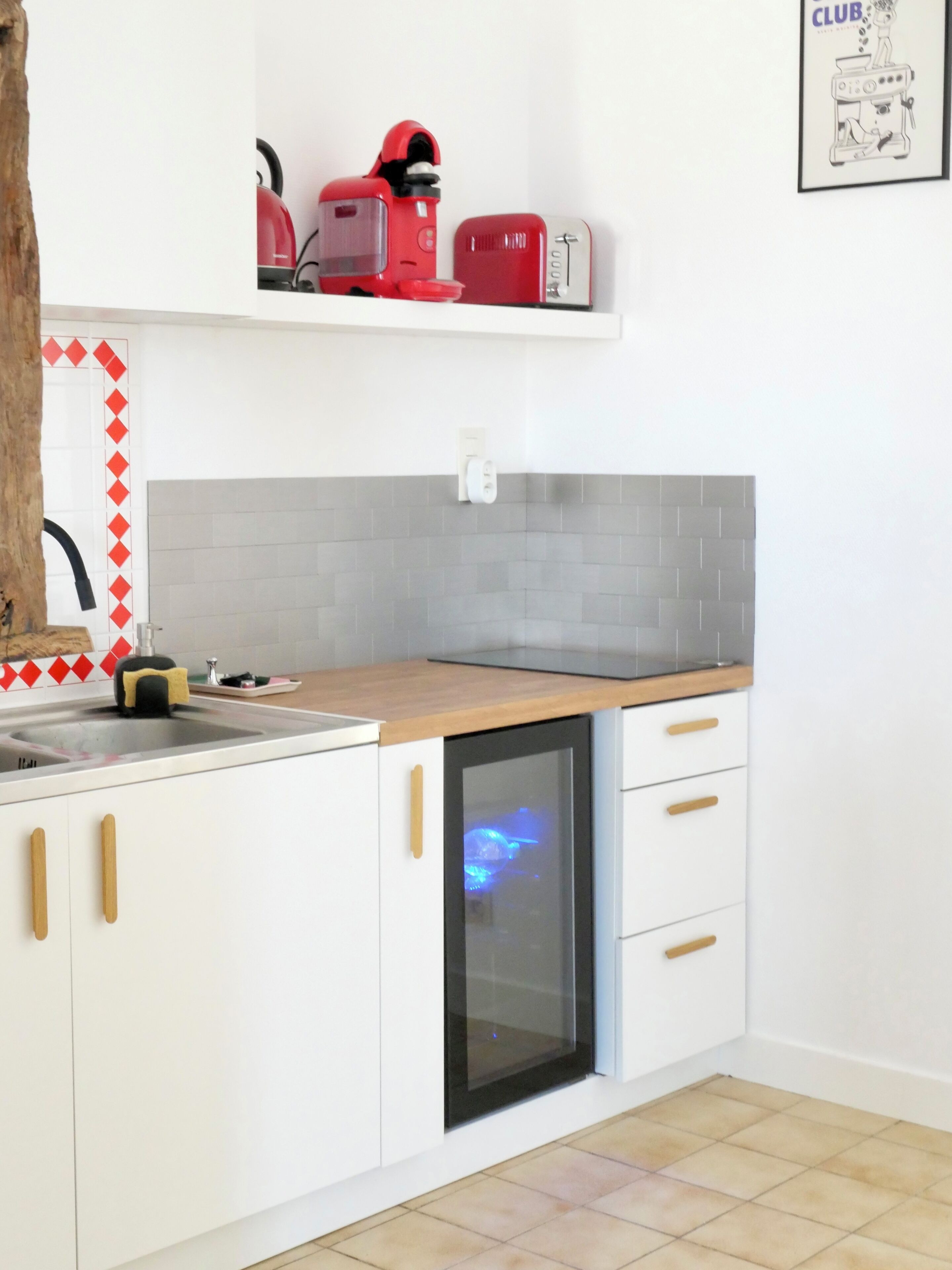 A kitchen with white cabinets, a wooden countertop, a built-in dishwasher, and a red toaster.