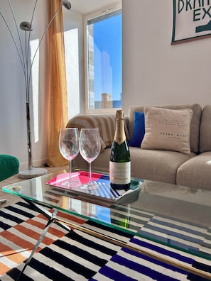 Una mesa de vidrio con una botella de vino, dos copas de vino y un tapete a rayas.