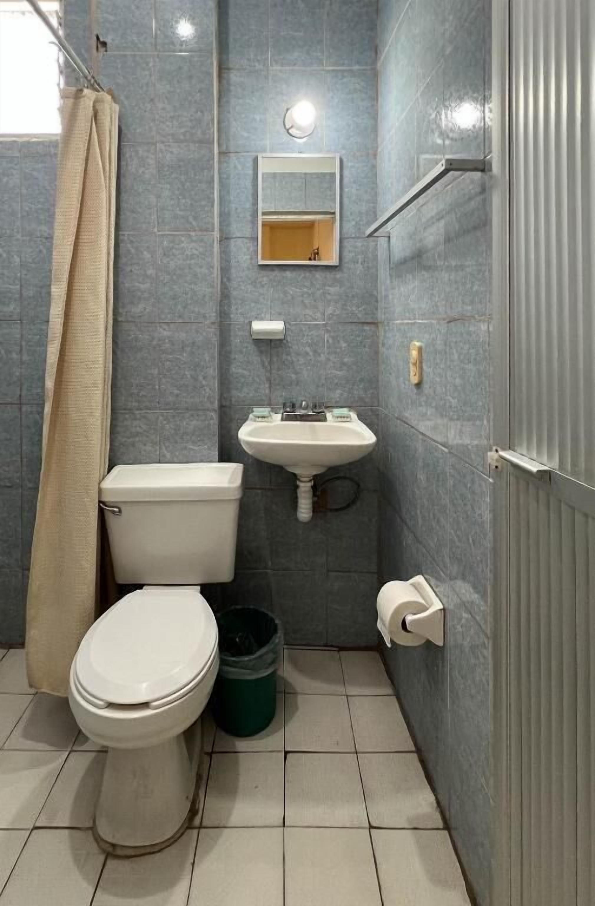 A bathroom with a toilet, sink, and mirror.