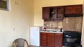 Una cocina funcional con refrigerador, estufa, lavamanos y gabinetes de madera.
