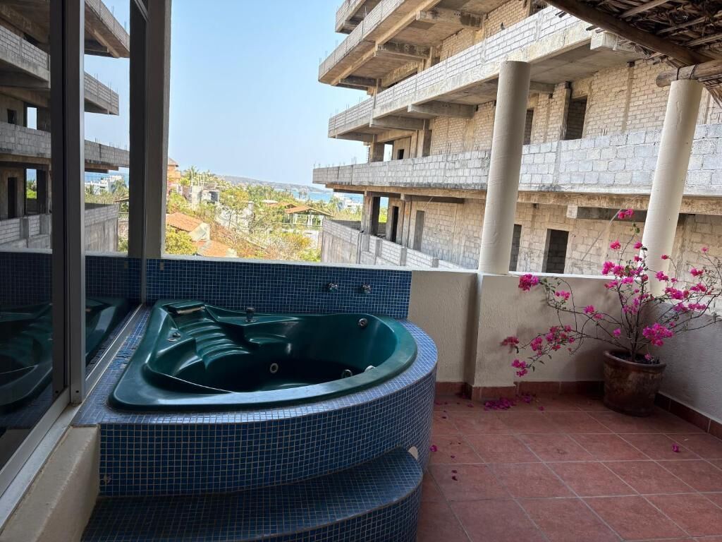 Eine Dachterrasse mit Whirlpool, Topfpflanzen und Blick auf die umliegenden Gebäude.