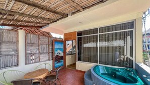 Un patio cubierto con comedor, un jacuzzi y un ventanal grande.