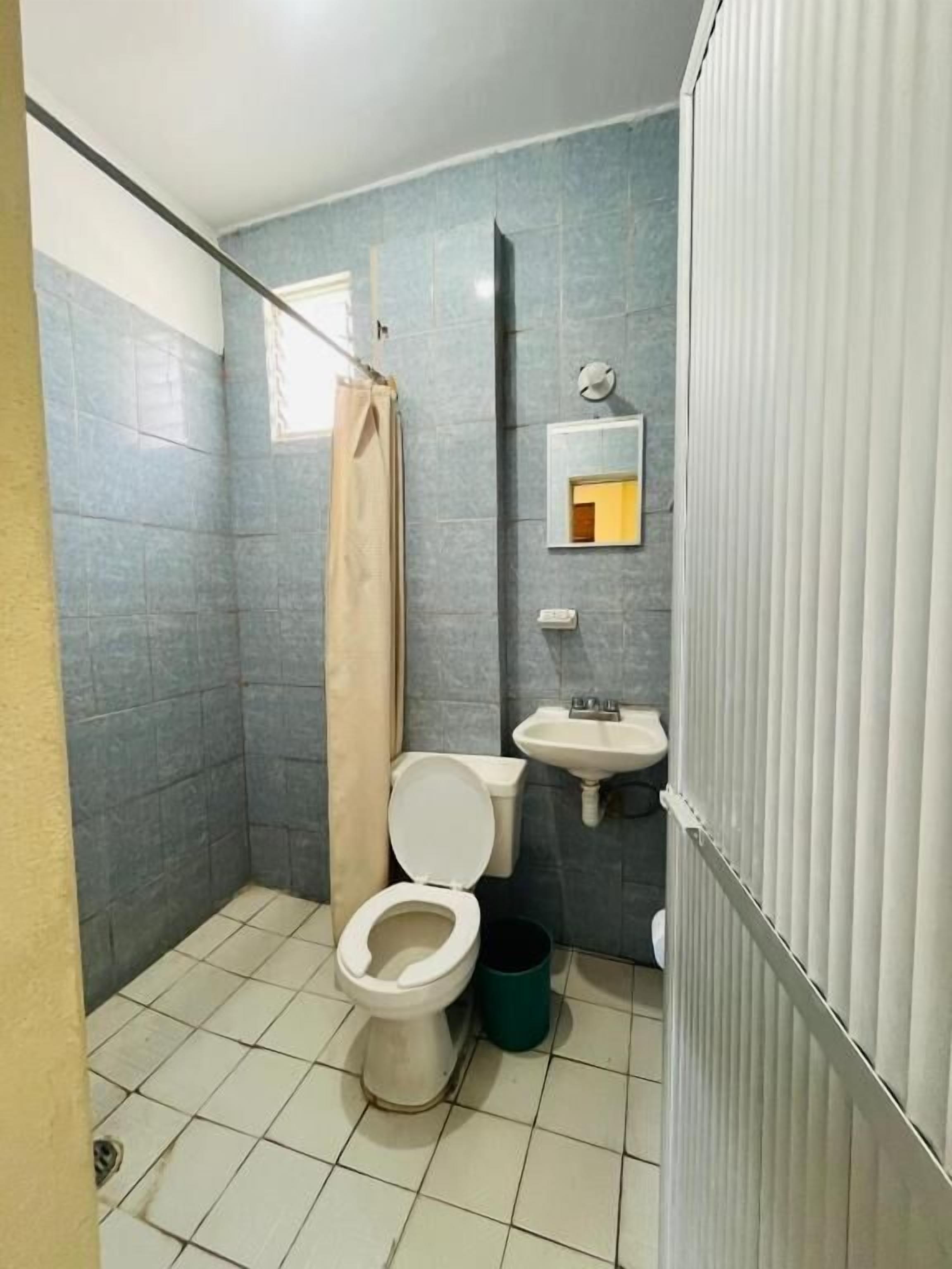 Un baño pequeño con inodoro, lavamanos y cortina de ducha.