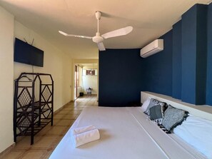 A hotel room with a bed, a ceiling fan, a TV mounted on the wall, and an air conditioning unit. - Casa piedra parada hotel (Brisas de Zicatela)