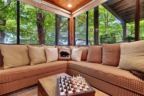 A cozy corner with a checkered sofa, a chessboard, and large windows overlooking a forest. - Dobie 26 with Wintergreen Advantage (Wintergreen)