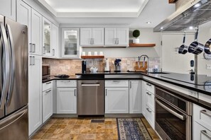 Una cocina moderna con electrodomésticos de acero inoxidable, armarios blancos y piso estampado.