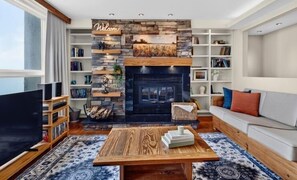 A modern living room with a fireplace, bookshelves, a sofa, and a coffee table. - Ledges 73 with Wintergreen Advantage (Wintergreen)