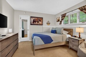 A bedroom with a bed, bedside tables, a dresser, a television, and a window with blinds. - Laurelwood 00 with Wintergreen Advantage (Wintergreen)