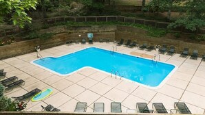Ein rechteckiger Pool mit Fliesen umgeben, mit Liegestühlen und einer kleinen Whirlwanne.