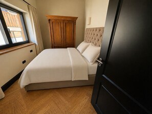 A bedroom with a bed, a wardrobe, a window, and a door. - New Chalets in the Tannheimer Valley (Jungholz)