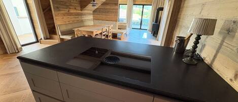 Una cocina moderna con una isla central, vigas de madera y vistas al área de comedor.