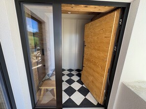 A modern interior with a checkered floor, a wooden door, and a glass door leading outside. - New Chalets in the Tannheimer Valley (Jungholz)