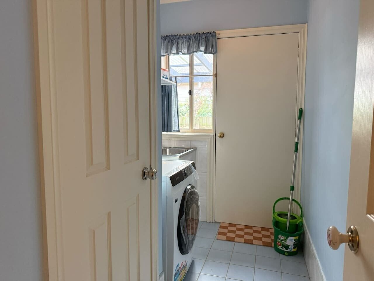 Une buanderie équipée d’un lave-linge, d’une serpillière et d’un seau.