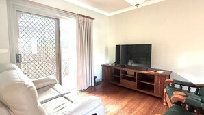 Ein Wohnzimmer mit einer Couch, einem Fernsehschrank und einer Schiebetür.