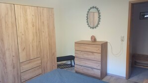Una camera da letto con un'armadio in legno, un comodino, uno specchio e una panca.