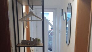 Un corridoio con un'unità di scaffalature in metallo nero, un tavolo in legno e uno specchio appeso al muro.