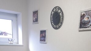 Zona pranzo con un tavolo rettangolare, quattro sedie, una sveglia a muro e due quadri incorniciati.