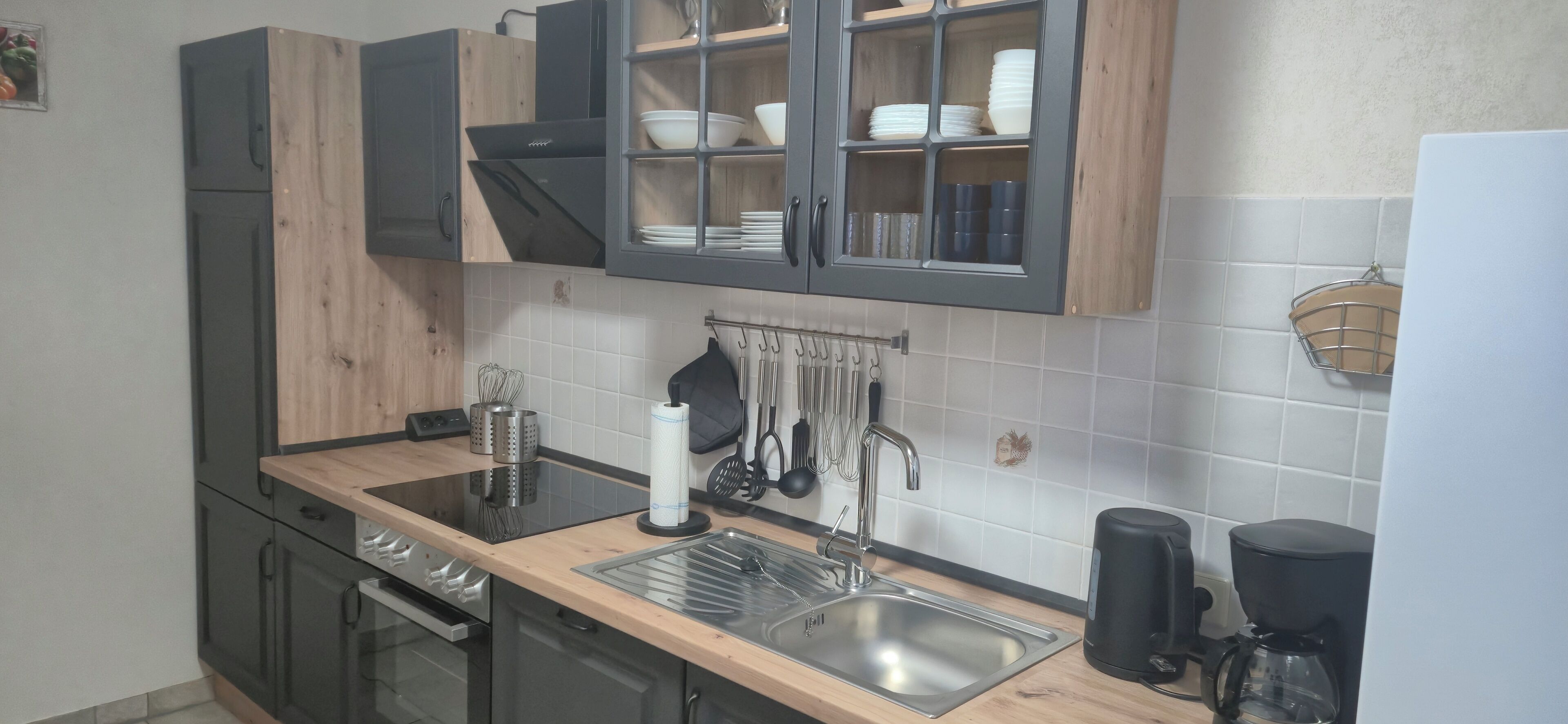 Una cocina moderna con horno empotrado, pileta de acero inoxidable y cafetera.