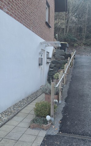 A residential area with a paved driveway, a stone retaining wall, and a wooden fence.