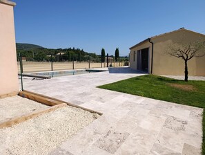 A courtyard with a swimming pool, a small garden area, and a building with a door. - Villa de Judith Roaix Provence (Roaix)