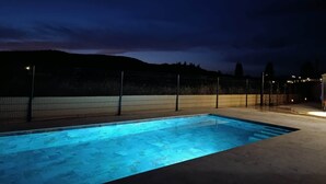 En rektangulær swimmingpool med et mørkt område omkring og et hegn.