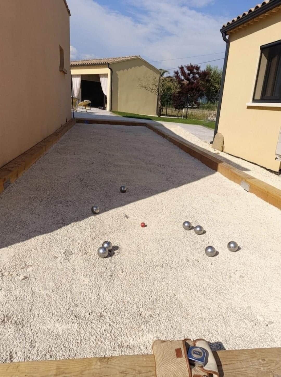 Un patio con suelo de grava, un banco de madera y una bolsa de equipo.