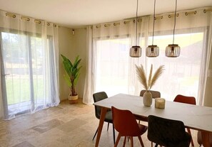 A dining area with a table, chairs, and hanging pendant lights. - Villa de Judith Roaix Provence (Roaix)