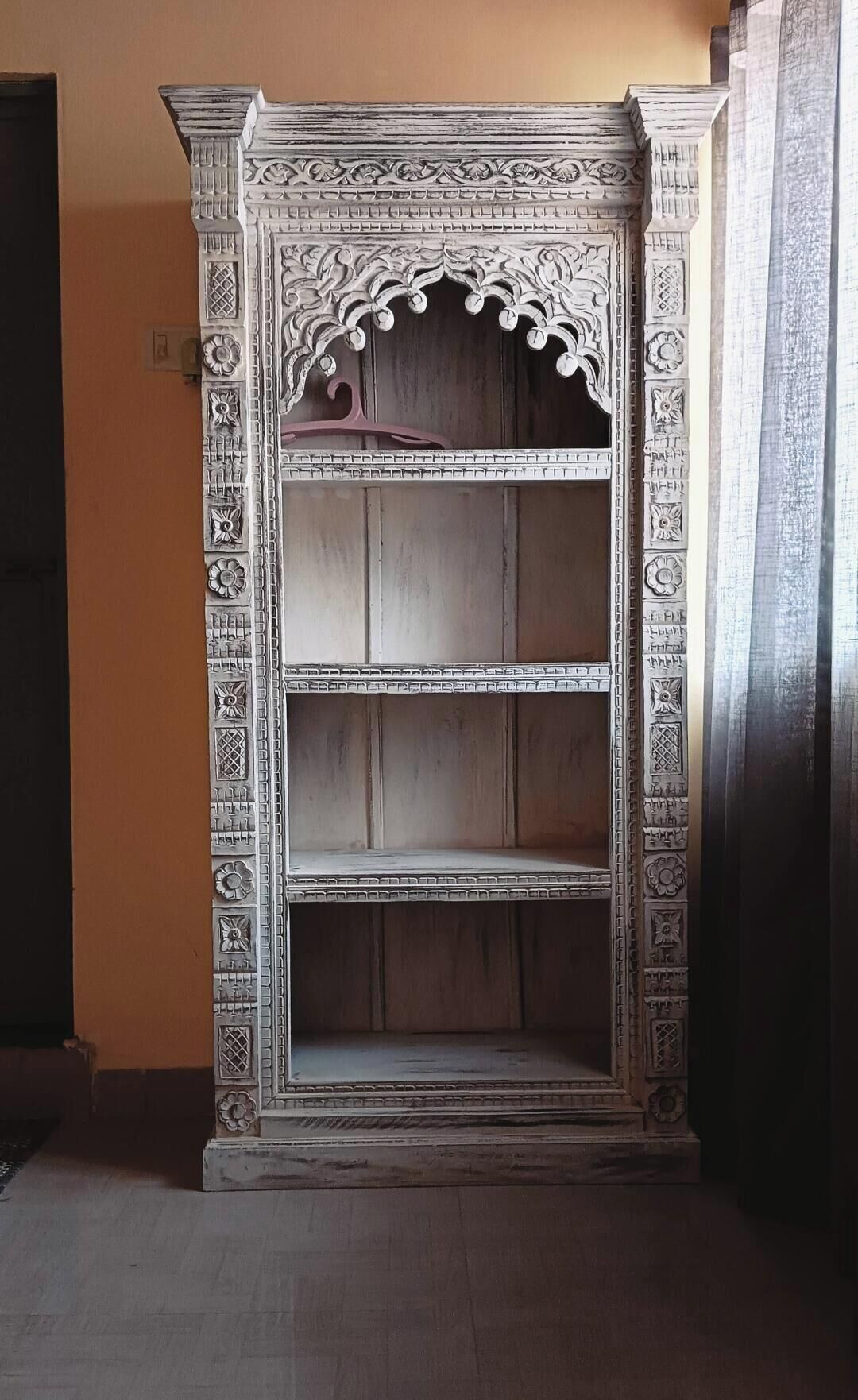 Eine dreistöckige, aufwendig geschnitzte Holzvitrine mit Verzierungen oben und einem Griff an der obersten Ablage.