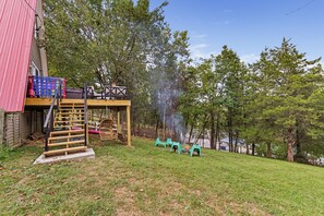 A backyard with a wooden deck, a swing, and a fire pit.