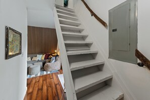 A staircase leading to a living area with a sofa and ottomans.