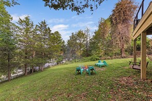A grassy outdoor area with a wooden deck, a fire pit, and outdoor seating.