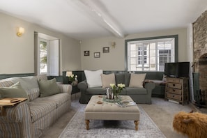 A cozy living room with a sofa set, a coffee table, a fireplace, and a television. - Thomas Street House -  a cottage that sleeps 6 guests  in 3 bedrooms (Cirencester)