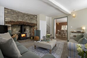 A cozy living room with a stone fireplace, a television, and comfortable seating. - Thomas Street House -  a cottage that sleeps 6 guests  in 3 bedrooms (Cirencester)