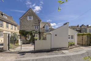 A residential street with stone houses, a gated entrance, and a clear sky. - Thomas Street House -  a cottage that sleeps 6 guests  in 3 bedrooms (Cirencester)