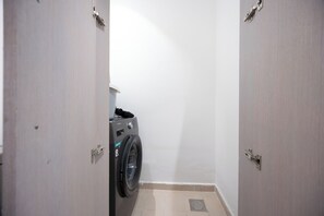 A laundry room with a washing machine, a door, and a tiled floor. - Bloomfields 2BR in Waters Edge 9  (Abu Dhabi)