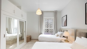 Een hotelkamer met een groot bed, een nachtkastje met een lamp, een spiegel en uitzicht op een gebouw.