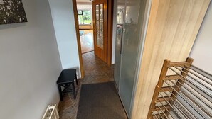A hallway with a door leading to a room, a small table, and a metal rack. - Modern family friendly house in Reykjavik area (Garðabær)