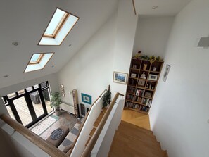 Ein geräumiges Zimmer mit Oberlichtern, einer Holztreppe und einem Bücherregal.