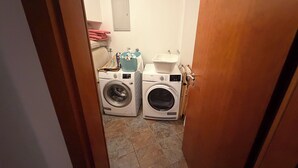 A laundry room with two front-loading washing machines, a drying rack, and a small sink. - Modern family friendly house in Reykjavik area (Garðabær)