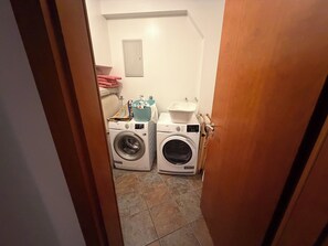 Ein Waschraum mit zwei Waschmaschinen mit Frontlader, einem Wäscheständer und einem kleinen Waschbecken.