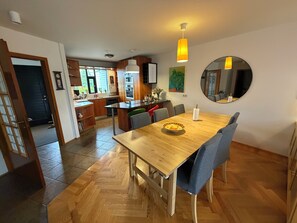 A modern kitchen with wooden cabinets, a central island, and a dining area with a wooden table and chairs.