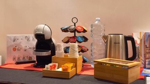 Ein Tisch mit einer Kaffeemaschine, einer Wasserflasche, einem Wasserkocher und verschiedenen Speisen.