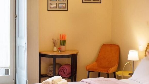 Ein Hotelzimmer mit einem Bett, einem Sessel, einem Tisch mit Handtüchern und Wandbildern.