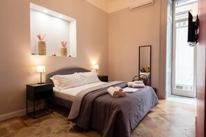 Quarto de hotel com cama, mesas de cabeceira, espelho e janela.