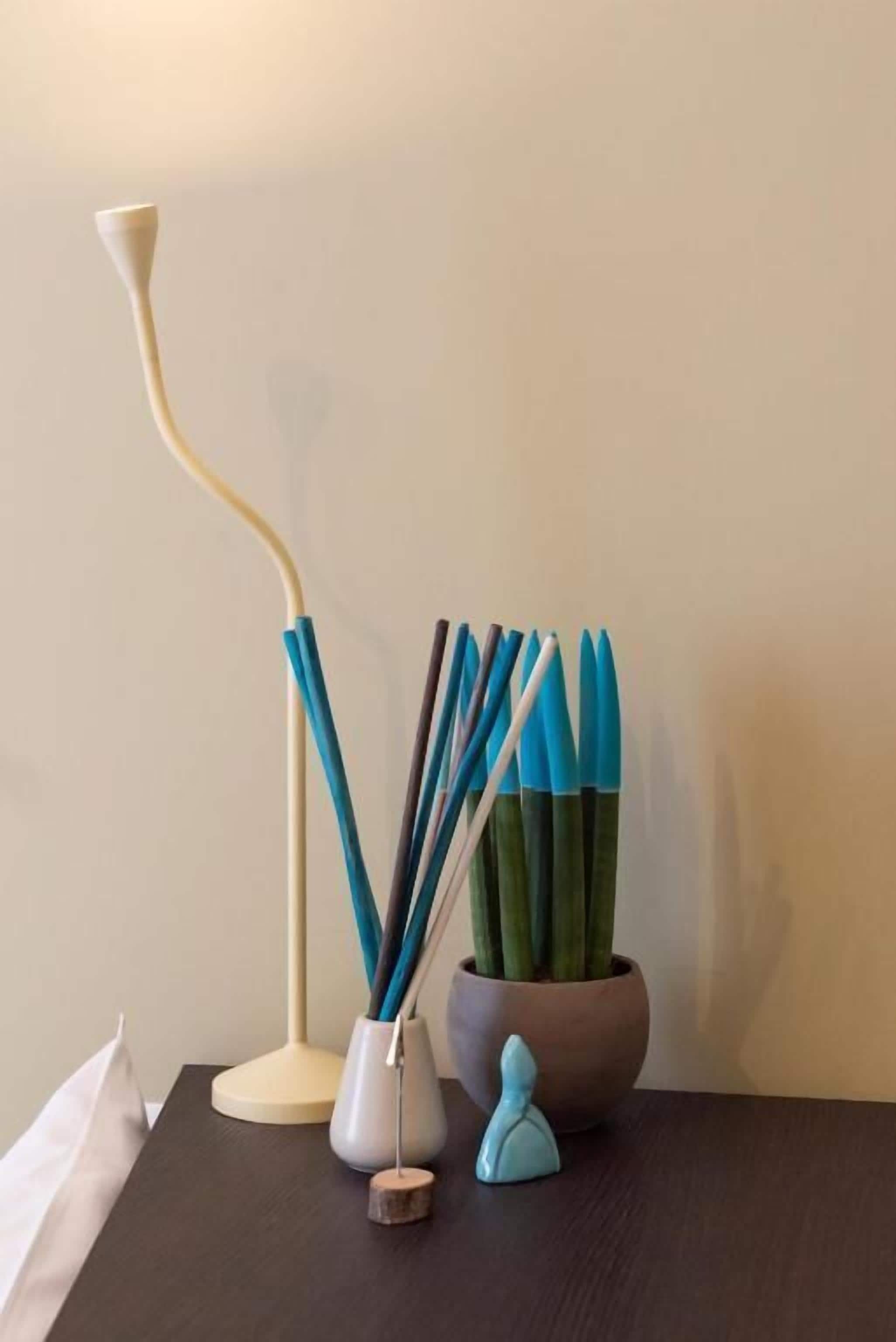 A table with a lamp, a vase with sticks, and a small figurine.