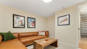 Ein Zimmer mit einem braunen Ledersofa, einem Holztisch und zwei gerahmten Postern an der Wand.