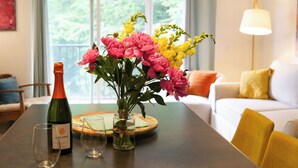 A dining table with a bottle of wine, a glass, and a vase with flowers. - 1BR, 2nd Floor Condo at Sugarbush (Warren)