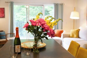 Ein Esstisch mit einer Weinflasche, einem Glas und einer Blumenvase.
